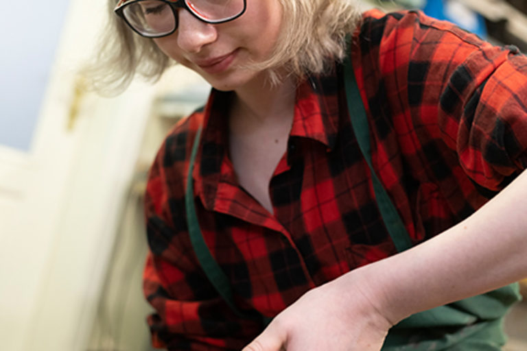 Eine Auszubildende mit einer Schusterzange beim Arbeiten an einem Leisten in einer orthopädischen Werkstatt.