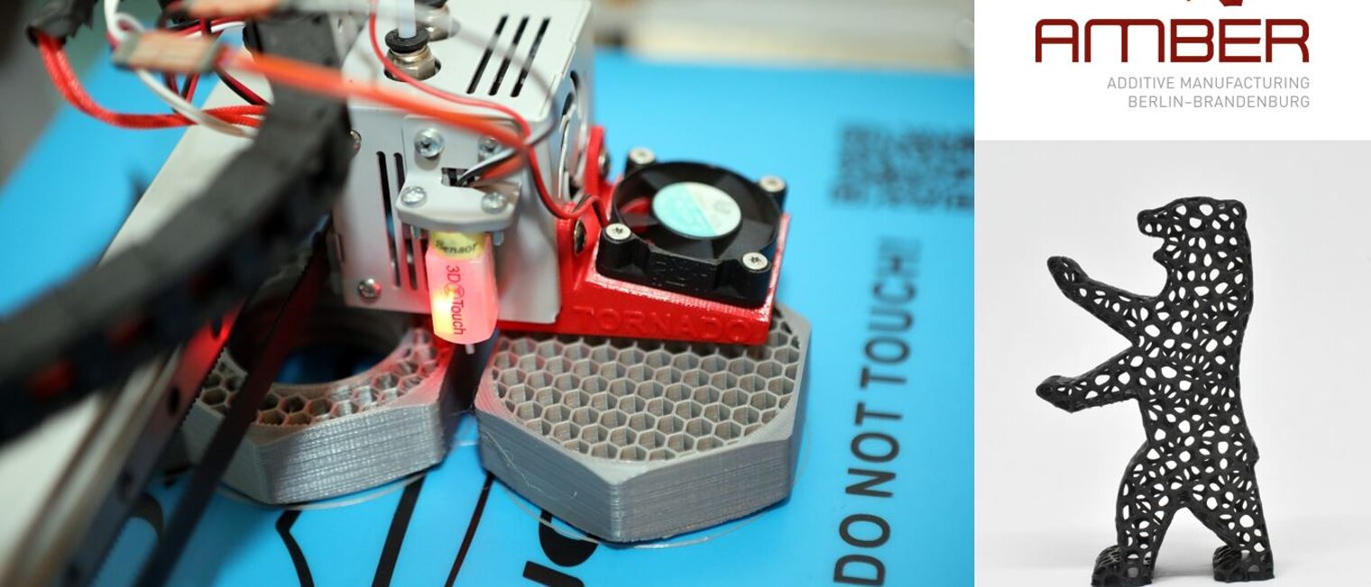 AMBER-Kombi-Logo - Zu sehen ist der Druckkopf eines 3D-Druckers sowie ein graues Druckobjekt: Sechskant 
